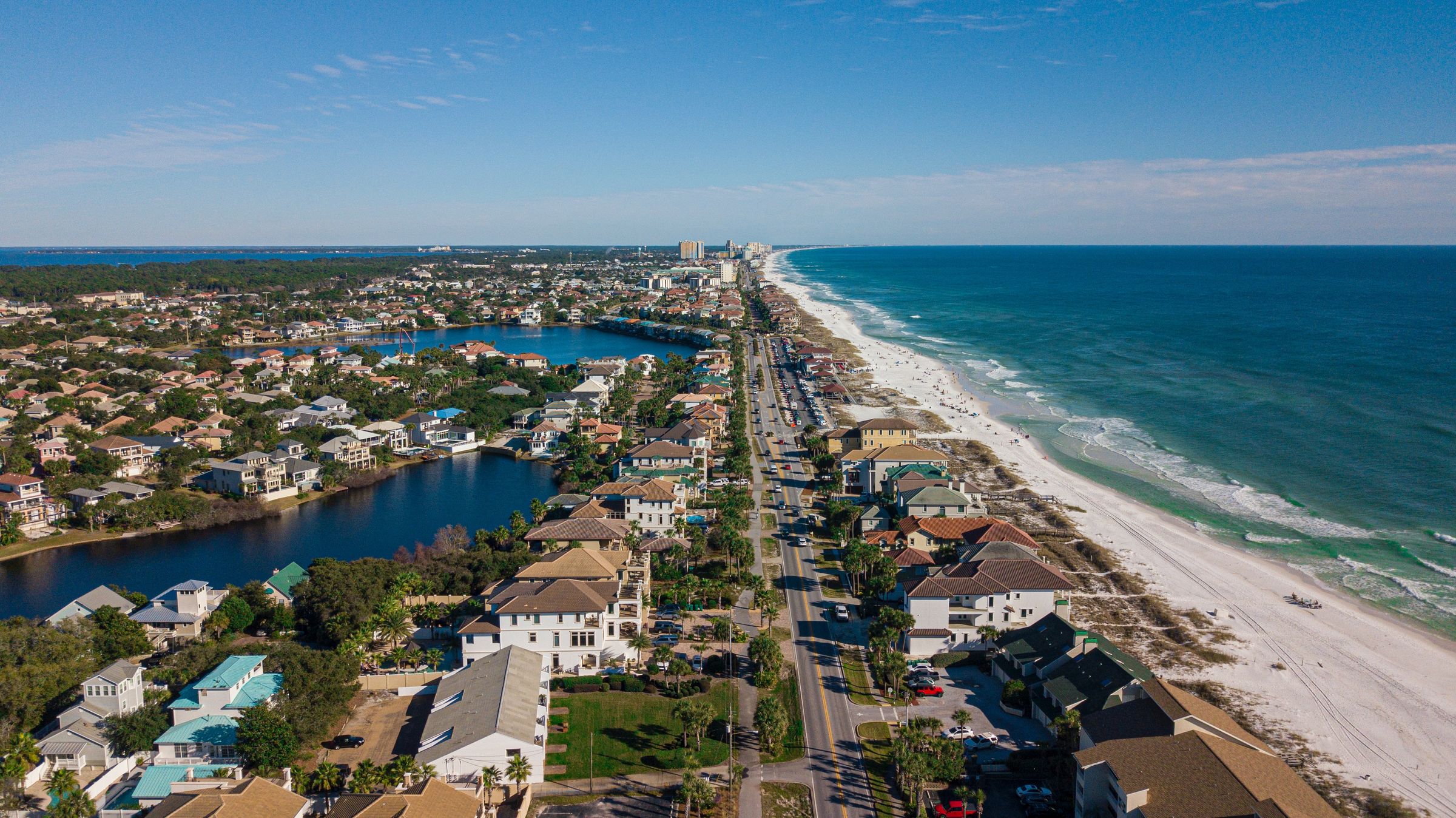 Florida coastal homes between a lake and a sandy beach with blue water