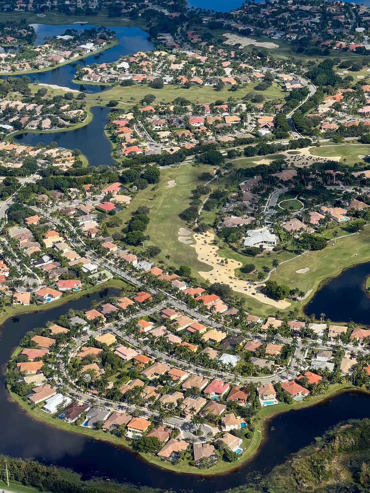 Wide aerial view of Florida homes surrounded by lakes, trees, and open green spaces